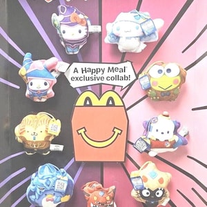 Peut inclure: Un ensemble de huit peluches représentant Hello Kitty et ses amis habillés en personnages de la franchise Yu-Gi-Oh! Les peluches sont présentées sur un fond rose et violet avec le texte "Yu-Gi-Oh! x Hello Kitty and Friends" et "A Happy Meal exclusive collab!"