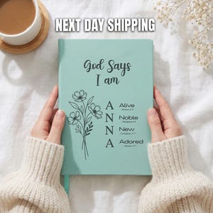 May include: A light mint green journal featuring the black text God Says I am, a floral illustration, and the vertical name ANNA with the words Alive, Noble, New, and Adored, each accompanied by a corresponding Bible verse reference.