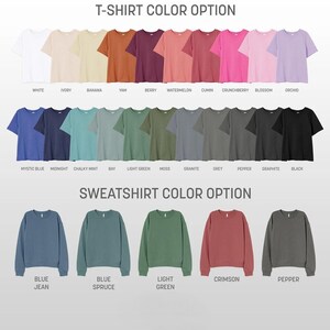 Op de afbeelding: Een grafiek met t-shirt- en sweatshirtkleuropties. De t-shirtkleuren zijn: wit, ivoor, banaan, yam, bes, watermeloen, komijn, bosbes, bloesem, orchidee, mystiek blauw, middernacht, krijtwitte munt, baai, lichtgroen, mos, graniet, grijs, peper, grafiet en zwart. De sweatshirtkleuren zijn: jeansblauw, blauwspar, lichtgroen, karmijnrood en peper.