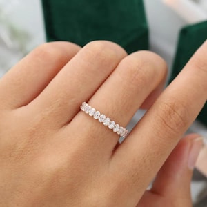 May include: A delicate eternity band featuring a row of sparkling round diamonds set in a polished metal band.