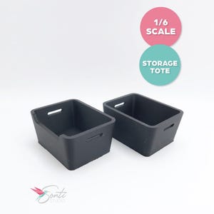 May include: Two black storage totes with handle cutouts. The totes are rectangular and have a slightly trapezoidal shape. The text "1/6 SCALE" and "STORAGE TOTE" are in the background.