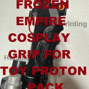 Puede incluir: Una empuñadura negra impresa en 3D para un paquete de protones de juguete. La empuñadura tiene una superficie texturizada y una perilla plateada en el lateral. El texto "FROZEN EMPIRE COSPLAY GRIP FOR TOY PROTON PACK" está impreso en rojo sobre un fondo blanco.