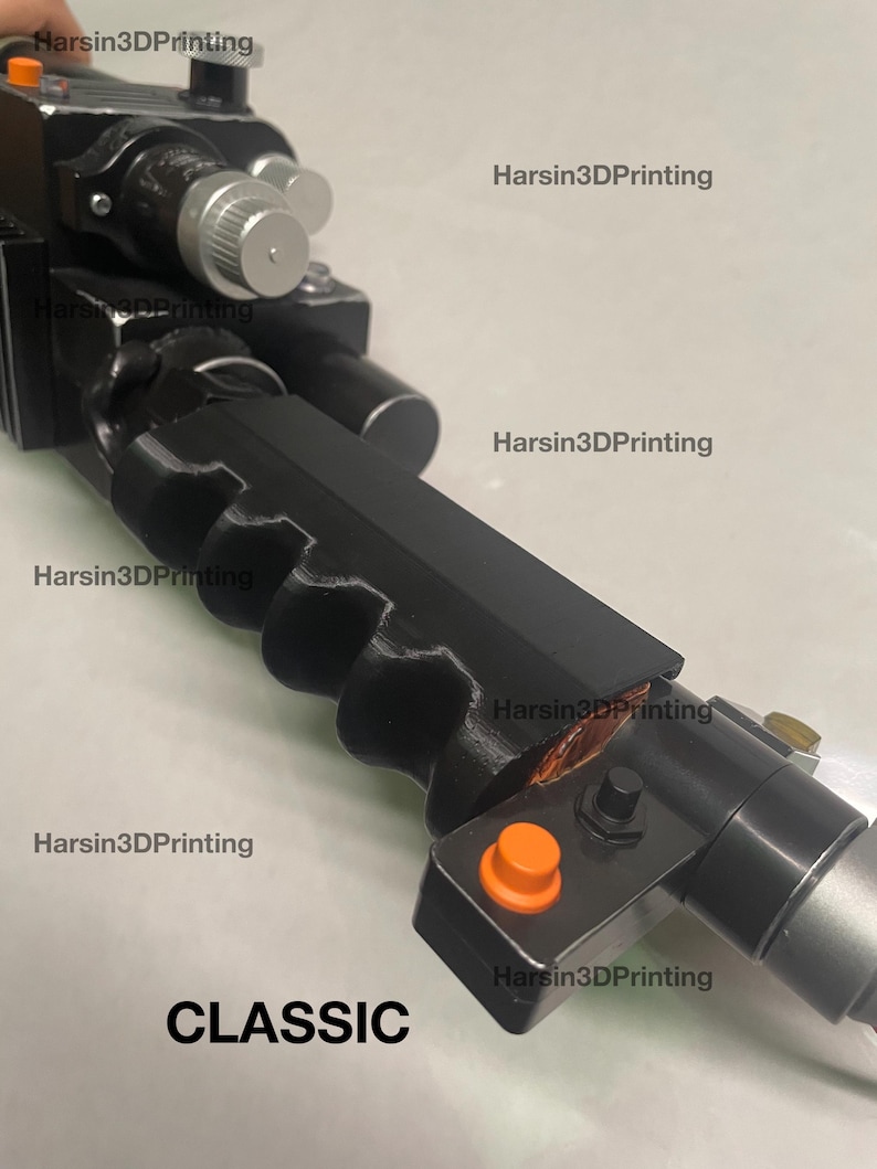May include: A black plastic toy gun with an orange button and the word "CLASSIC" printed on the bottom. The gun has a textured grip and a silver barrel.