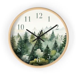 May include: A round wooden wall clock with black hands and white numbers. The clock face features a watercolor illustration of a misty forest with green trees.