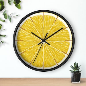 May include: A black framed clock with a yellow lemon slice design. The clock face has black hands and a black center.
