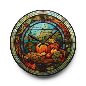 May include: A stained glass clock with a fall harvest theme. The clock face features a depiction of pumpkins, grapes, and leaves in shades of orange, green, and brown. The clock hands are black.
