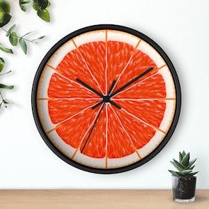 May include: A black wall clock with a grapefruit slice design. The grapefruit is red and has a white center. The clock hands are black.