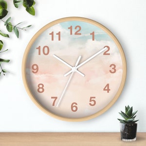 May include: A round, wooden-framed clock with a white face and pink and blue watercolor clouds. The clock has black hands and brown numbers.