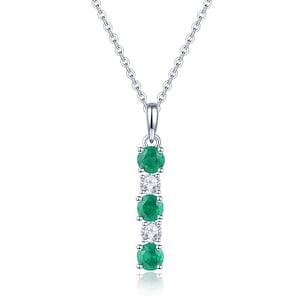 May include: A silver necklace with a pendant featuring five round gemstones. The pendant has three green emeralds and two white diamonds arranged vertically.