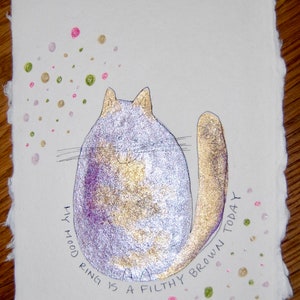 May include: A hand-drawn illustration of a purple and gold cat with the text "My mood ring is a filthy brown today" written around it. The background is white with scattered pink, green, and gold dots.
