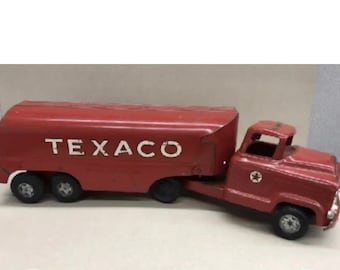 Könnte beinhalten: Roter Spielzeug-LKW mit einem Tankwagen-Anhänger. Der Anhänger hat das Wort "TEXACO" in weißen Buchstaben auf der Seite. Der LKW hat einen roten Stern an der Seite.