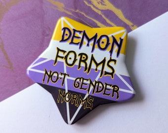 May include: A yellow, purple, and black star-shaped button with the text "Demon Forms Not Gender Norms" in black.