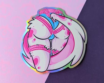 May include: A holographic sticker featuring a cartoon illustration of a creature with white and pink skin, tied with pink rope. The creature has large, rounded features and is set against a pink and purple background.