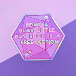 Könnte beinhalten: Ein sechseckiger holografischer Aufkleber mit einem geometrischen Polyeder-Design in Lila- und Rosatönen. Der Text lautet: BEING A DUMB LITTLE GAY BITCH IS A FREE ACTION. Kleine Sternsymbole befinden sich an den oberen und unteren Ecken der Form.