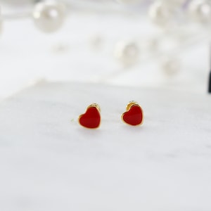 May include: A pair of gold heart-shaped earrings with red enamel.