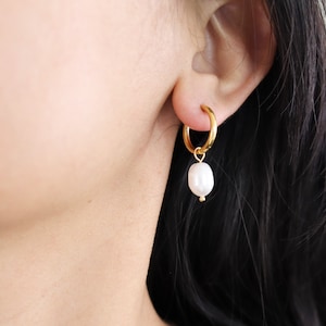 Könnte beinhalten: Goldene Creolen mit einem einzelnen weißen Perlenanhänger an jeder Creole.