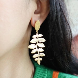 May include: Gold leaf earrings with a delicate, cascading design. The earrings are long and feature multiple leaves connected by a thin stem.
