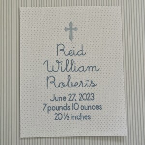 May include: A white card with blue text announcing the birth of Reid William Roberts. The card includes the date of birth, June 27, 2023, and the baby's weight and length: 7 pounds 10 ounces and 20 1/2 inches.