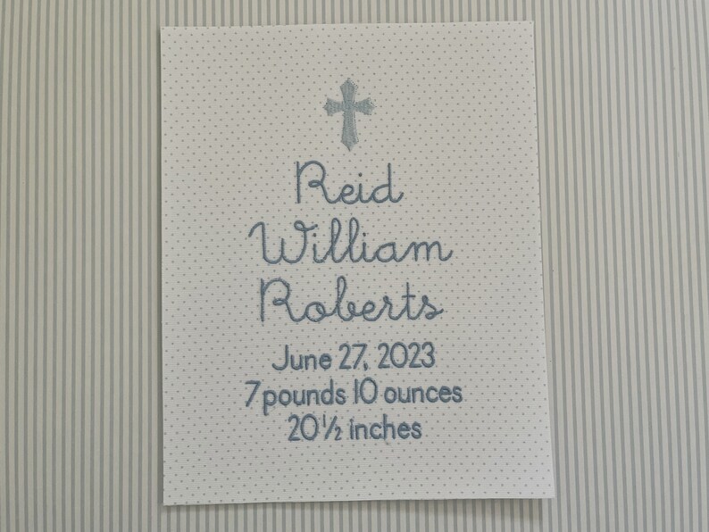 May include: A white card with blue text announcing the birth of Reid William Roberts. The card includes the date of birth, June 27, 2023, and the baby's weight and length: 7 pounds 10 ounces and 20 1/2 inches.