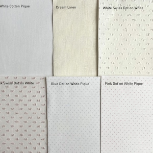 May include: A selection of fabric swatches showcasing different textures and patterns. Features white cotton pique, cream linen, white Swiss dot on white, pink Swiss dot on white, blue dot on white pique, and pink dot on white pique.