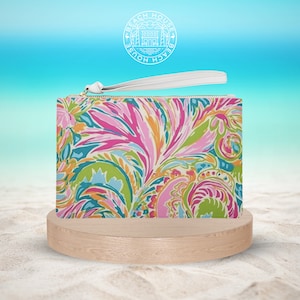 Puede incluir: Un bolso de mano blanco con una correa blanca y un estampado paisley colorido. El bolso tiene una cremallera dorada y las palabras "Beach House" están impresas en un círculo en la correa.