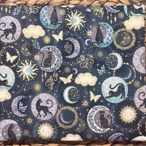 以下が含まれることがあります： 黒猫、月、太陽、蝶、星が描かれた、暗い青色の生地。 金色、白、ラベンダー色のアクセントがデザインに含まれています。 この生地は、キルトや工芸品に使用される可能性があります。