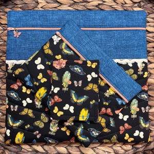 May include: A set of quilted fabric items featuring a butterfly theme. Includes a large blue zippered pouch, a smaller blue zippered pouch, and a black quilted item with a butterfly pattern. The background is a woven texture.