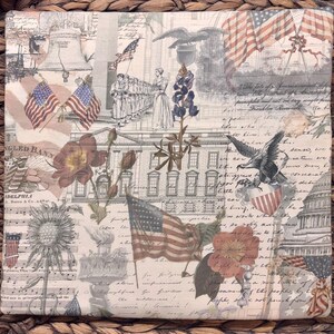 K&ouml;nnte beinhalten: Ein quadratischer Stoffuntersetzer mit einer Collage aus historischen amerikanischen Motiven, darunter die Liberty Bell, das Wei&szlig;e Haus, das Kapitol, amerikanische Flaggen, Wei&szlig;kopfseeadler, Blumen und kursiver Text.