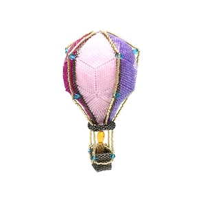 Könnte beinhalten: Ein Perlen-Heißluftballon-Anhänger mit einem rosa, lila und roten Ballon und einem goldenen Korb. Der Ballon ist mit blauen Perlen verziert.