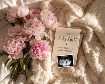 May include: A bouquet of pink peonies rests beside a card announcing "It's a Baby Girl!" with the baby's sonogram. The card also includes the baby's name and the expected birth month and year. The scene is set on a cream-colored blanket.