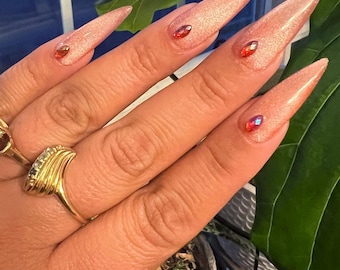 Uñas postizas cat eye color melocotón champán. Stiletto largo en la foto.