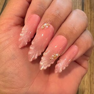 Pink cat eye seashell press on nails with pearls and gold balls. Long almond in pic.
