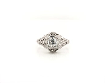 May include: A vintage-style diamond engagement ring with a delicate filigree design. The ring is set in platinum and features a round brilliant-cut diamond.