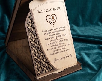 May include: A dark brown wooden display stand featuring a light-colored wooden plaque with the text BEST DAD EVER, a heart icon with two figures, and a heartfelt message of gratitude, framed by intricate laser-cut geometric side panels.