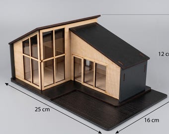 May include: A wooden model house with a black roof and light wood siding, featuring large windows and a black base. The model measures 25 cm in length, 16 cm in width, and 12 cm in height, as indicated by the dimension lines printed on the image.