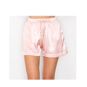 May include: Pink satin shorts with a drawstring waist.