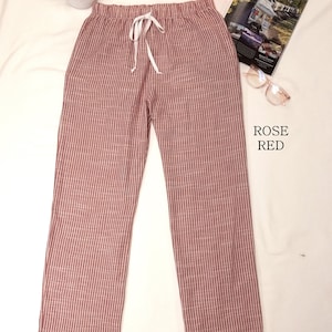 May include: Rose red striped pants with a white drawstring. The pants are made of a soft, comfortable fabric and have a relaxed fit.