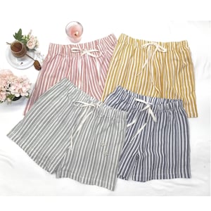 May include: Four pairs of striped shorts in different colors: pink, yellow, gray, and blue. The shorts have a drawstring waist and are made of a lightweight fabric.