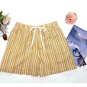 May include: Yellow and white striped linen shorts with a white drawstring tie.