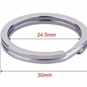 May include: A silver key ring with a 24.5 mm inner diameter and a 30 mm outer diameter.