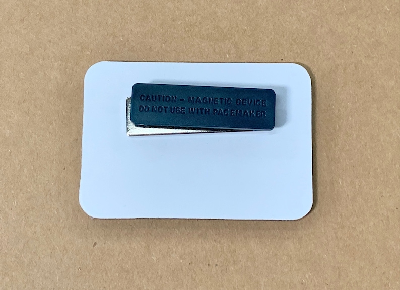 May include: A white rectangular name tag with a black magnetic strip that reads "CAUTION - MAGNETIC DEVICE DO NOT USE WITH PACEMAKER".