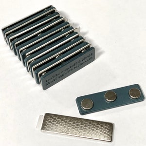 May include: A stack of 10 dark grey magnetic name tag holders with the text "CAUTION - Magnetic Device Do Not Use With Pacemaker" printed on the side. A separate name tag holder with three magnets is also shown.