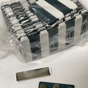 May include: A pack of 25 black and white striped magnetic name tags with a silver magnetic name tag and a gray magnetic name tag with three magnets.
