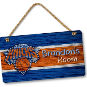 May include: A blue and orange wooden sign with the New York Knicks logo and the text "Brandon's Room".