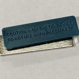 May include: A blue rectangular magnet with the text "CAUTION - MAGNETIC DEVICE DO NOT USE WITH PACEMAKER" on it.