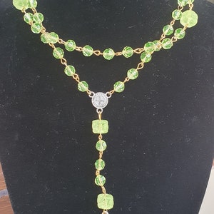 Op de afbeelding: Een groene glazen rozenkrans met een zilveren kruis en een zilveren medaillon hanger.