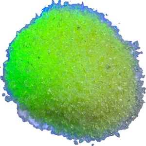 Puede incluir: Un montón de material granular fino con un vibrante color amarillo verdoso neón. La textura parece cristalina y reflectante, con partículas individuales que captan la luz para crear un aspecto brillante y luminoso sobre un fondo blanco.