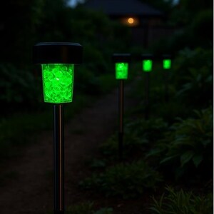 K&ouml;nnte beinhalten: Eine Reihe von vier solarbetriebenen Wegbeleuchtungen mit gr&uuml;nen LED-Lichtern. Die Lichter befinden sich auf einem Weg in einem Garten bei Nacht.