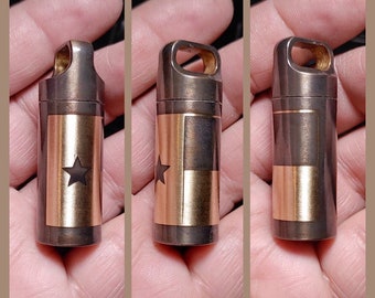 May include: A small, round, metal container with a gold-colored Texas flag design. The container has a loop at the top for attaching to a keychain.