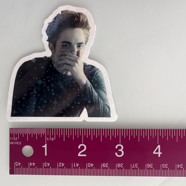 May include: A die-cut sticker featuring a portrait of a person with light skin, brown hair, and a dark shirt. The shirt has a pattern of stars. The sticker is approximately 3 inches in length.